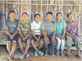  ?? ?? The shamans of the Tikuna indigenous ethnic group (from left) Ivan Angarita, Eugenio Ramirez, Dionisio Manduca, Alejandro Parente, and Camilo Ramoz and the representa­tive of the indigenous council Marbella Ramos (second right) sit on a wooden bench at the Arara community in the Amazon region, Colombia.