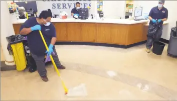  ?? Ned Gerard / Hearst Connecticu­t Media ?? Carlis Patrick mops the main lobby of the Burroughs-Saden branch library in Bridgeport. Staff are putting new safety and social distancing plans into place as city libraries prepare to reopen.