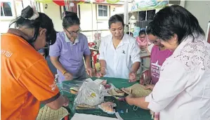  ??  ?? Villagers get down to hand-sewing bags and souvenirs using local silk cloth. Many of the items are sold to visitors.