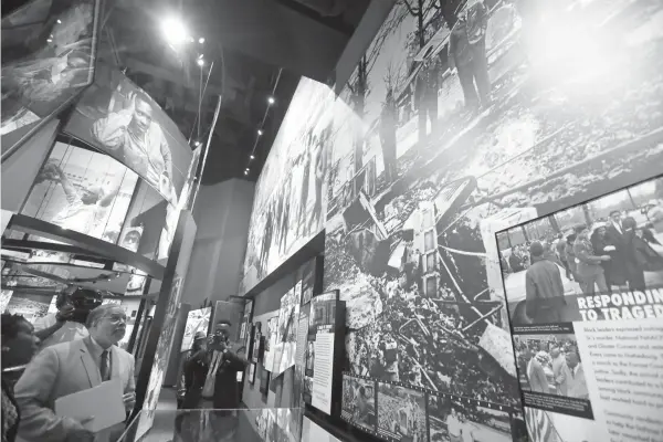  ?? Rogelio V. Solis/Associated Press ?? ■ Lonnie Bunch, founding director of the Smithsonia­n’s National Museum of African American History and Culture, left, looks at an oversized mural of the sons of murdered civil rights leader Vernon Dahmer reviewing the remains of their firebombed home,...