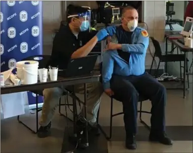  ?? PHOTO COURTESY OF MONTGOMERY COUNTY DEPARTMENT OF PUBLIC SAFETY ?? Second Battalion Chief Anthony McGrail from the Second Alarmers Rescue Squad gets a vaccine shot from Dr. Alvin Wang, chief medical officer for the Montgomery County Department of Public Safety.