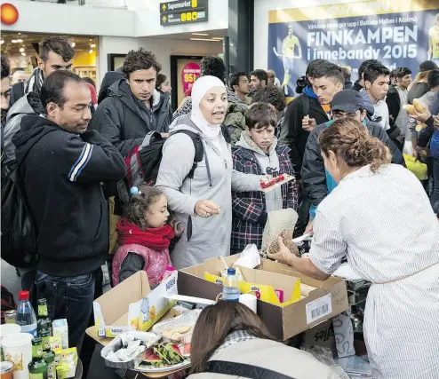  ?? OLA TORKELSSON / AFP / GETTY IMAGES FILES ?? Food and drink is distribute­d by volunteers to refugees at Malmoe train station in Malmoe, Sweden, in 2015.