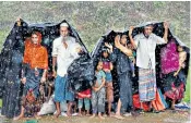  ??  ?? Rohingya women, who crossed over from Burma into Bangladesh (above), stretch their arms out to collect sanitary products from aid agencies; refugees in a camp in Cox’s Bazar, top left; families use a makeshift shelter as monsoon rains hit the camps, left