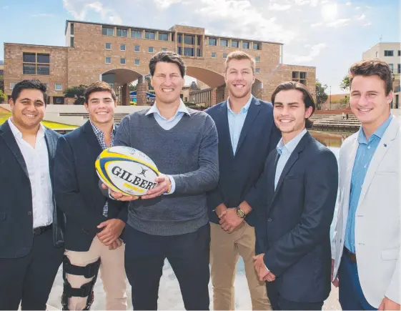  ?? Picture: CAVAN FLYNN ?? Rugby statesman John Eales (with ball) and scholarshi­p winners (from left) Gavin Luka (commerce), Dylan Riley (sports management), Angus Blyth (commerce), Maxwell Dowd (architectu­re) and Lachlan Connors (sport science) at the Bond University campus.