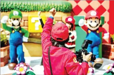  ?? AFP ?? Fans (centre, obscured) pose for photograph­s with Super Mario Bros. characters Mario (right) and Luigi (left) during a media preview of the Super Nintendo World at Universal Studios in Osaka.