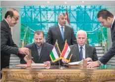  ?? AFP ?? Fatah’s Azzam al-Ahmad (R) and Saleh al-Aruri (L) of Hamas signing a reconcilia­tion deal in Cairo. — file picture