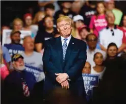  ?? — AFP ?? US President Donald Trump listens as West Virginia Governor Jim Justice announces that he is switching parties to become a republican during the president’s campaign rally at the Big Sandy Superstore Arena on Aug 3, 2017 in Huntington, West Virginia.