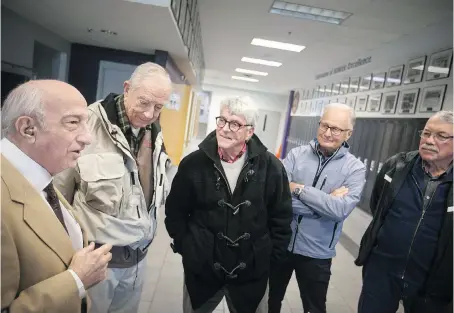  ?? DAX MELMER/WINDSOR STAR ?? Assumption Catholic High School alumni, from left, Edward Alice, Phillip Milan, Charles West, Drew Mathany and John Lesperance share old stories in the hallway of the school before attending the 50th and 70th reunions of the school on Saturday.