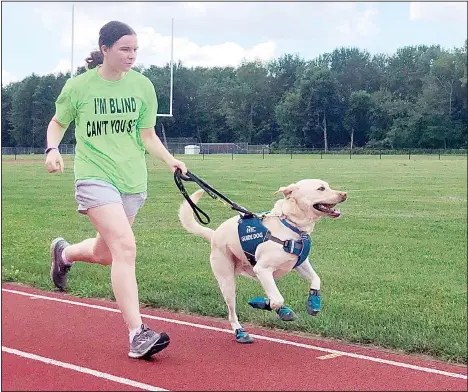  ??  ?? Megan Hale, who is visually impaired, runs on the high school track near her home in West Sand Lake, N.Y., with her guide dog Hero in this July 20, 2020 photo.
Hero is from Guiding Eyes for the Blind, which developed a program to train dogs to guide blind runners during workouts in addition to daily activities. (AP)