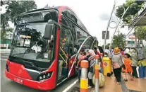  ?? AHMAD KHUSAINI / JAWA POS ?? BERJUBEL: Suroboyo Bus disesaki penumpang. Kebanyakan di antara mereka adalah ibu-ibu dan anak-anak. Foto atas, ibu-ibu mengganden­g putra-putri mereka naik bus.