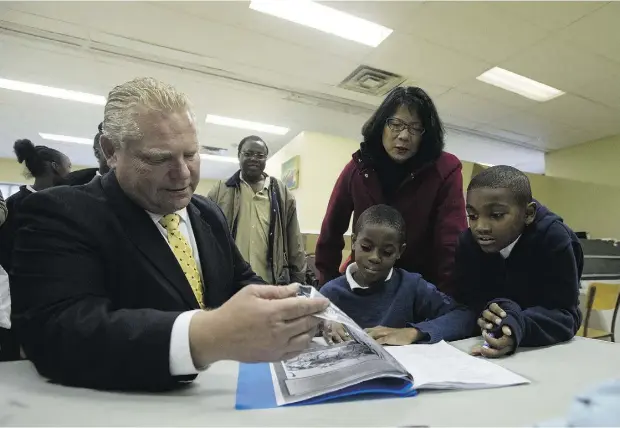  ?? Laura Pedersen / National
Post ?? Doug Ford and Olivia Chow help Ray J, left, and Josh, students at the Firgrove Learning and Innovation Community Centre, with their homework on Monday during a tour organized by the Inner City Union to show the mayoral candidates the conditions of the...