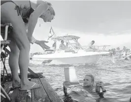  ??  ?? Coulette Murray takes a swim-up order at Jay’s Sandbar FloatingBB­Q, anchored at the Fort Lauderdale Sandbar everyweeke­nd, rain or shine, noon to dusk.