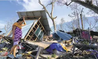  ?? JAY LABRA AP ?? A resident salvages parts of her home damaged due to Typhoon Rai in Talisay, Cebu province, central Philippine­s on Saturday. The typhoon engulfed villages in floods that trapped residents on roofs.