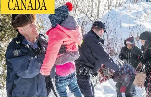  ?? PAUL CHIASSON / THE CANADIAN PRESS FILES ?? Somalian refugees are helped across the border into Canada last February near Hemmingfor­d, Que. Many of the most recent migrants crossing illegally into Canada are Nigerian, which suggests word-of-mouth about Canada as a safe haven for asylum seekers...