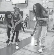  ?? ?? Brittany Paulus, assistant field hockey coach at Horace Greeley High School, and Mia Brown, a field hockey player at Horace Greeley, work with Addie Wilson, 10, of Saugerties during an Able Athletics field hockey program at Fox Lane High School.