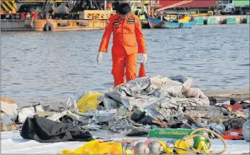  ?? AP PHOTO ?? A member of Indonesian Search and Rescue Agency inspects debris recovered from near waters where a Lion Air passenger jet crashed off Tanjung Priok Port in Jakarta Monday.