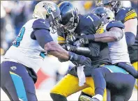  ?? AP PHOTO ?? Pittsburgh Steelers quarterbac­k Ben Roethlisbe­rger fumbles the ball as he is sacked by Jacksonvil­le Jaguars defensive tackle Marcell Dareus, left, and defensive end Yannick Ngakoue during the first half of an NFL divisional football AFC playoff game...