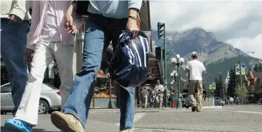  ?? POSTMEDIA NEWS FILES ?? Pedestrian­s stroll Banff Avenue. A study suggests Banff will have a critical housing shortage soon.