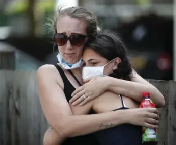  ?? TOLGA AKMEN/AFP/GETTY IMAGES ?? Two women embrace after writing messages on a wall of condolence following the blaze at Grenfell Tower.