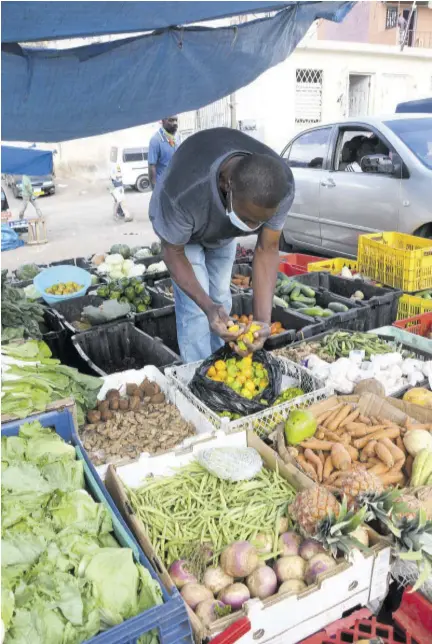  ?? ?? Fifty-five-year-old produce vendor Bertram Young, who was busy packing a bag with peppers, says he has no problem selling outside the Christiana Market.