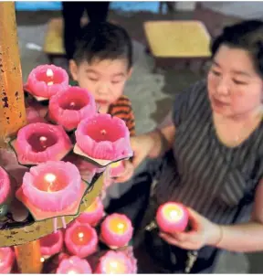  ??  ?? Praying together: Michelle Neoh, 44, and her son Yeoh Yuan Hao, three, lighting candles for prayers at Hong Hock See Temple in Jalan Perak, Penang.
