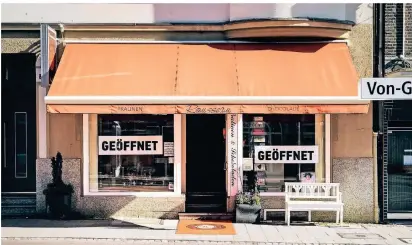  ?? FOTO: A. KREBS ?? Rousseau Chocolade in Düsseldorf hat „Geöffnet“-Schilder im Schaufenst­er. Ab Montag dürfen auch viele Non-Food-Geschäfte wieder loslegen.