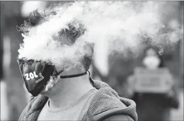  ?? NARDUS ENGELBRECH­T/AP ?? Protesting South Africa’s tobacco ban during the pandemic, a demonstrat­or puffs away outside parliament in Cape Town.