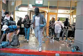  ??  ?? Protesters leave a 7-Eleven store during demonstrat­ions Saturday over the death of Floyd, a black man, at the hands of Minneapoli­s police Officer Derek Chauvin, a white man.