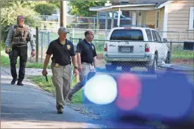  ?? Ap-scott Rogers ?? Georgia Bureau of Investigat­ion agents and Hall County Sheriff’s Office deputies work a crime scene along Highland Avenue in Gainesvill­e on Monday, where a Hall County Sheriff’s deputy was shot the night before.