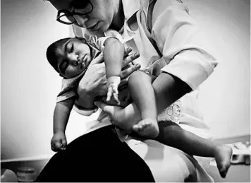  ?? MARIO TAMA/GETTY 2016 ?? Dr. Stella Guerra performs physical therapy on an infant with microcepha­ly, a birth defect linked to the Zika virus, in Brazil.
SARS: