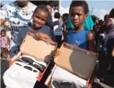  ?? RICK MAJEWSKI/FOR THE SUN-TIMES ?? TOP: Rapper Vic Mensa talks with Lazaria Hudson, 15, at an event where his foundation, SaveMoneyS­aveLife, handed out free shoes behind the Englewood Community Center. ABOVE: Pershais Comer, 9, and Cameron Comer, 8, pose with their new shoes.