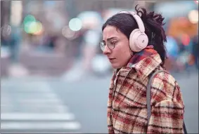  ?? ANDRES KUDACKI/AP PHOTO ?? A woman uses her headphones Tuesday while walking in New York. After the relative quiet of the pandemic, New York City has come roaring back.