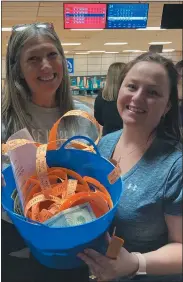  ?? ?? Event volunteers Renee Murray and Alicia Funke show off a portion of the donated dollars from raffle tickets to the bowling benefit at Sterling Lanes in Sterling Heights.