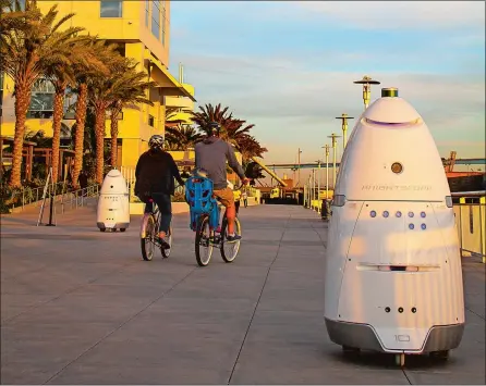  ?? STACY DEAN STEPHENS VIA AP ?? Knightscop­e K5 security robots, at right and background left, patrol alongside a pier in San Diego. The robots can identify a vehicle parked in a certain location for too long or sense intruders at odd hours. The company expects to have several large...