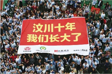  ??  ?? Above and below: Children orphaned by the devastatin­g Wenchuan earthquake and volunteers return to Ankang Home to mark the 10th anniversar­y. The huge banner reads: “Ten years since Wenchuan earthquake, we have grown up.” — Xinhua