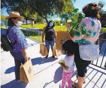  ?? NELVIN C. CEPEDA U-T ?? Sandra Mendoza (center) and Elizabeth Castro (left) canvass a Spring Valley park offering informatio­n and distributi­ng bags filled with various items from spare batteries to hand sanitizer.