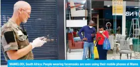  ?? — AFP ?? MAMELODI, South Africa: People wearing facemasks are seen using their mobile phones at Mams Mall near Pretoria on March 29, 2020.