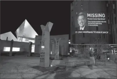  ?? The Associated Press ?? SIGN: The face of Sen. Cory Gardner, R-Colo., accompanie­d by words and moving text, which is part of an environmen­tal protest and unauthoriz­ed art installati­on is displayed Tuesday on the wall of the Denver Art Museum, in Denver.