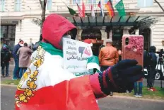  ?? AFP ?? ■ A protester with the Lion and Sun flag of the National Council of Resistance of Iran takes a selfie in front of the Grand Hotel.