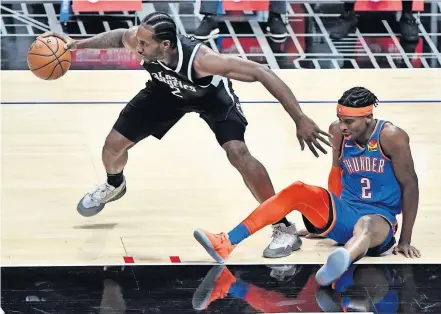  ??  ?? Clippers forward Kawhi Leonard (2) picks up a loose ball as Thunder guard Shai Gilgeous-Alexander (2) falls to the floor during the first quarter of Los Angeles' 108-100 win Sunday at Staples Center. [ROBERT HANASHIRO/USA TODAY SPORTS]