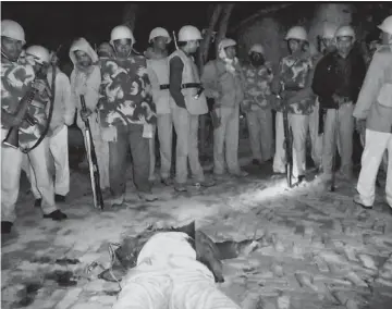  ?? — PTI ?? The body of DSP Zia- ul- Haq is seen lying on the ground as policemen stand guard in Pratapgarh on Saturday night. The DSP had received gunshots during exchage of fire between the police and the villagers following the murder of the village chief.
