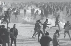  ?? AP PHOTO ?? Palestinia­n protesters run for cover from tear gas fired by Israeli troops during a demonstrat­ion near the Gaza Strip border with Israel, in eastern Gaza City.