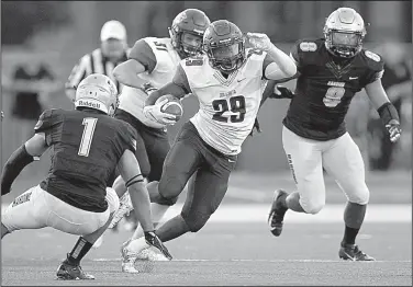  ?? Arkansas Democrat-Gazette/THOMAS METTHE ?? Ouachita Baptist running back Shun’cee Thomas (29) looks for running room between Harding defensive back Daylon Markham (1) and defensive lineman T.J. Winslow on Saturday during the second quarter of the Tigers’ 7-3 victory over the Bisons in Searcy.