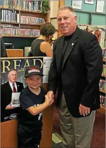  ??  ?? Assemblyma­n John McDonald III stands with a young child next to a photo of the assemblyma­n promoting summer youth reading while visiting the North Greenbush library.