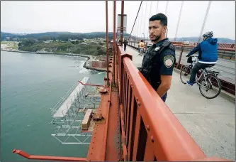  ??  ?? Patrol officer Nicolas Serrano looks out Aug. 3 at a suicide barrier under constructi­on below the Golden Gate Bridge in San Francisco.