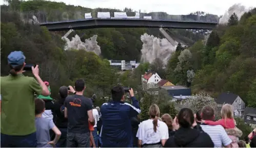  ?? AFP ?? BRIDGE BLASTING. People take pictures of the Rahmede highway bridge during its blasting on May 7, 2023 on the A45 motorway, near Luedensche­id, western Germany. During a routine inspection of the 453-meter-long Rahmede viaduct in December 2021, inspectors discovered deformatio­ns in the steel wall that could a ect the bridge’s load-bearing capacity. According to the motorway company, a new constructi­on will take at least  ve years.