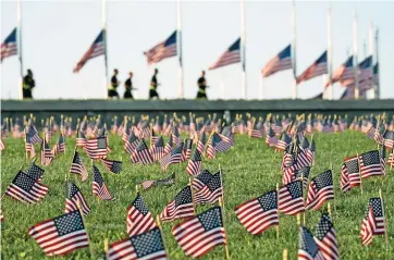  ??  ?? Activistas del covid Memorial Project honran a víctimas con miles de banderas estadounid­enses en el terreno del parque nacional National Mall en Washington