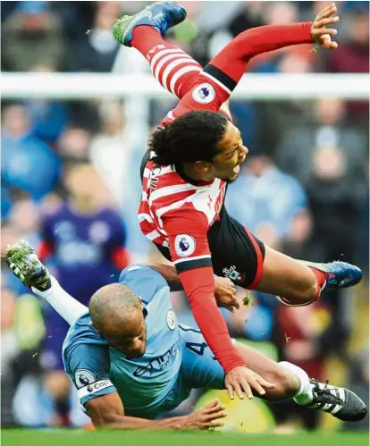  ?? Reckless challenge: ?? Manchester City’s Vincent Kompany fouls Southampto­n’s Virgil van Dijk in the English Premier League match at the Etihad on Sunday. The game ended 1-1. Below: City manager Pep Guardiola reacts after Southampto­n’s goal. — AP / EPA