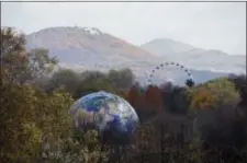  ?? RAINER JENSEN — DPA VIA AP ?? A globe and a Ferris Wheel stand in the forest near Bonn, Germany, Monday. The UN Climate Conference takes place in Bonn, Germany till.