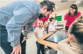  ??  ?? ● New interactiv­e table tablet for Cylch Meithrin Dolgellau, installed by Rawson Digital of Y Felinheli; Owen Evans is pictured enjoying the new table tablet with Arwel Griffiths of Rawson